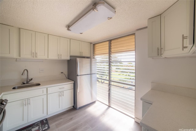 98-080 Uao Pl Unit C9, Aiea, HI 96701 - kitchen featuring a sink, freestanding refrigerator, a textured ceiling, white cabinetry, and light countertops