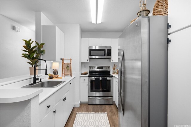 306 Mananai Pl Unit 4D, Honolulu, HI 96818 - kitchen with stainless steel appliances, a sink, wood finished floors, light countertops, and white cabinetry