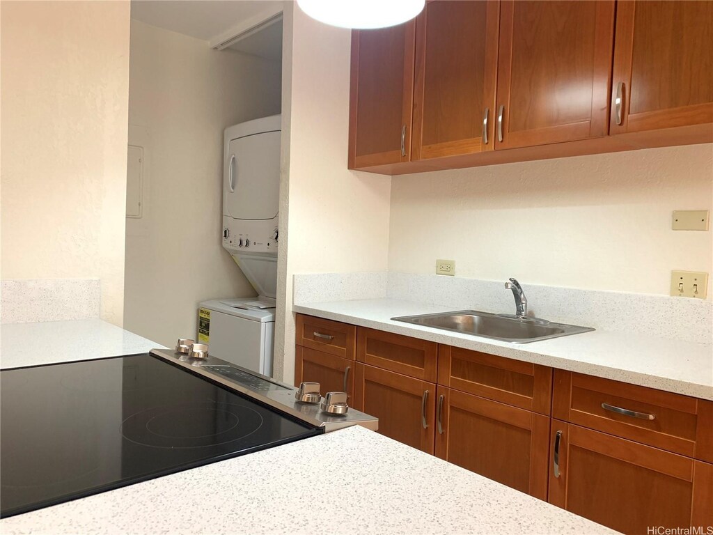 320 Liliuokalani Ave Unit 605, Honolulu, HI 96815 - kitchen featuring electric range oven, stacked washer / dryer, a sink, light countertops, and brown cabinets