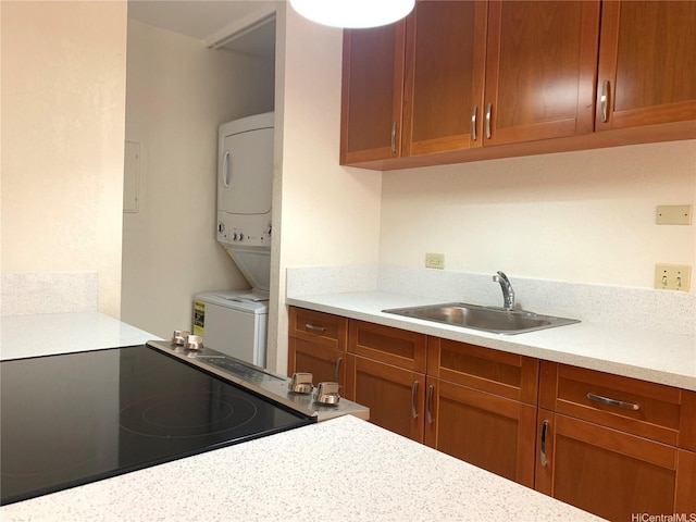 320 Liliuokalani Ave Unit 605, Honolulu, HI 96815 - kitchen featuring electric range oven, stacked washer / dryer, a sink, light countertops, and brown cabinets