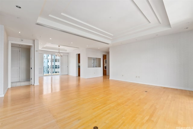 1740 S Beretania St Unit 10, Honolulu, HI 96826 - unfurnished living room featuring a raised ceiling, a chandelier, light wood-type flooring, and baseboards