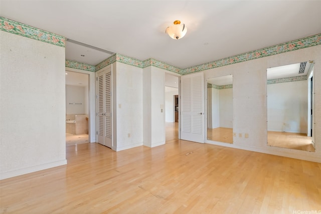1740 S Beretania St Unit 10, Honolulu, HI 96826 - unfurnished bedroom with wood finished floors, baseboards, wallpapered walls, and ensuite bathroom