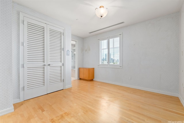 1740 S Beretania St Unit 10, Honolulu, HI 96826 - unfurnished bedroom with wood finished floors, a closet, wallpapered walls, and baseboards