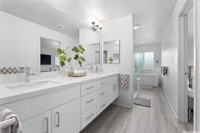 91-1669 Mee St, Ewa Beach, HI 96706 - bathroom with double vanity, wood finished floors, a soaking tub, and plenty of natural light