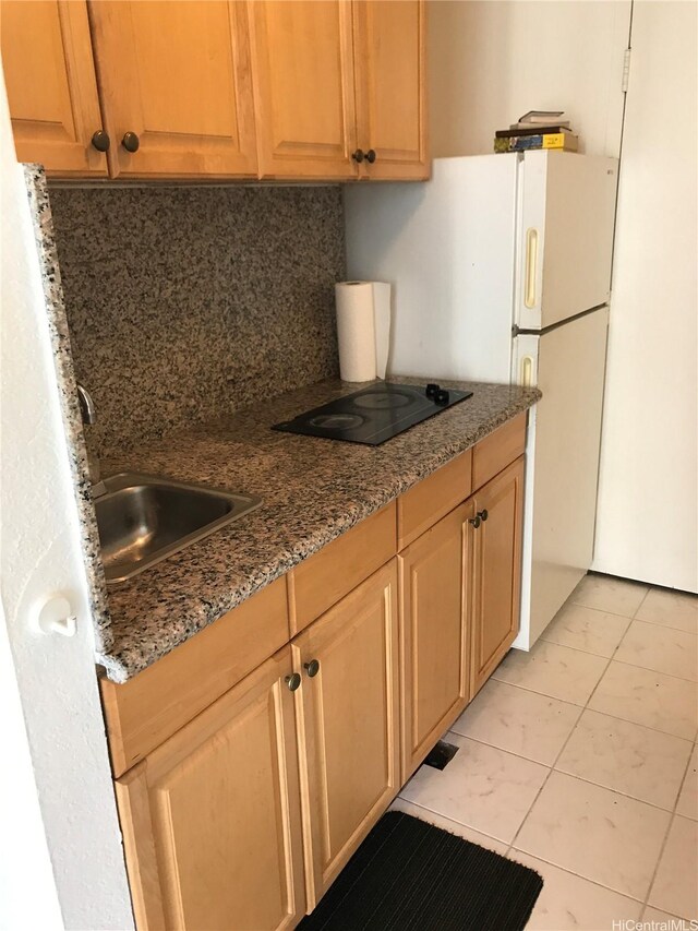 1920 Ala Moana Blvd Unit 1906, Honolulu, HI 96815 - kitchen with tasteful backsplash, black electric cooktop, dark stone counters, light tile patterned floors, and a sink