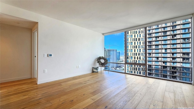 1001 Queen St Unit 2605, Honolulu, HI 96814 - spare room with expansive windows, hardwood / wood-style flooring, and a city view