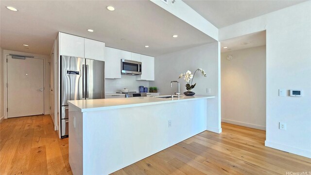 1001 Queen St Unit 2605, Honolulu, HI 96814 - kitchen featuring stainless steel appliances, a peninsula, light wood-style flooring, recessed lighting, and white cabinets