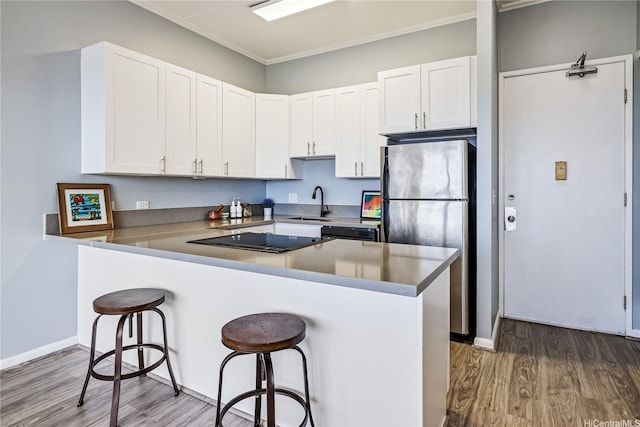 411 Hobron Ln Unit 3905, Honolulu, HI 96815 - kitchen with black appliances, wood finished floors, a breakfast bar area, a sink, and white cabinets