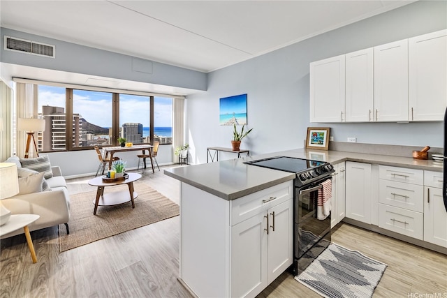 411 Hobron Ln Unit 3905, Honolulu, HI 96815 - kitchen featuring black / electric stove, a peninsula, white cabinetry, and light wood finished floors