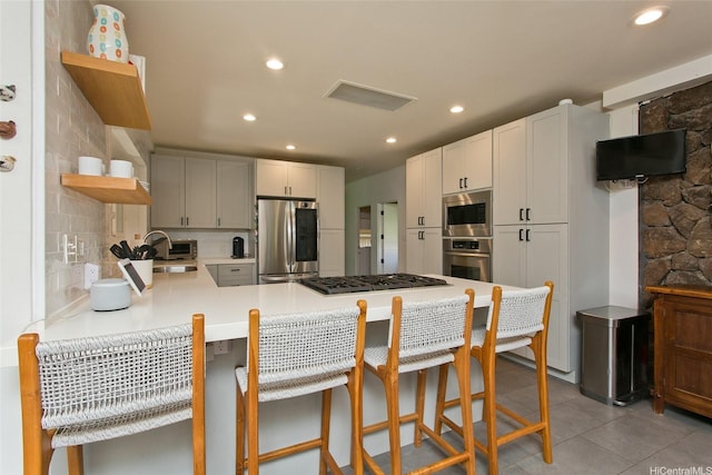 759 Elepaio St, Honolulu, HI 96816 - kitchen with stainless steel appliances, open shelves, a peninsula, a kitchen breakfast bar, and light countertops
