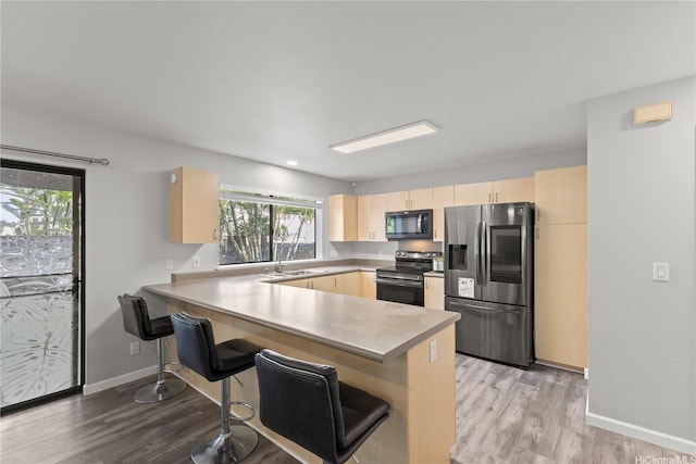 95-1039 Palamoa St Unit 107, Mililani, HI 96789 - kitchen featuring stainless steel appliances, light brown cabinets, a peninsula, light wood-style flooring, and baseboards