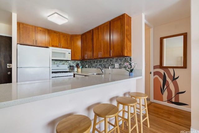 2452 Tusitala St Unit 1207, Honolulu, HI 96815 - kitchen with white appliances, decorative backsplash, brown cabinetry, a sink, and light wood-type flooring