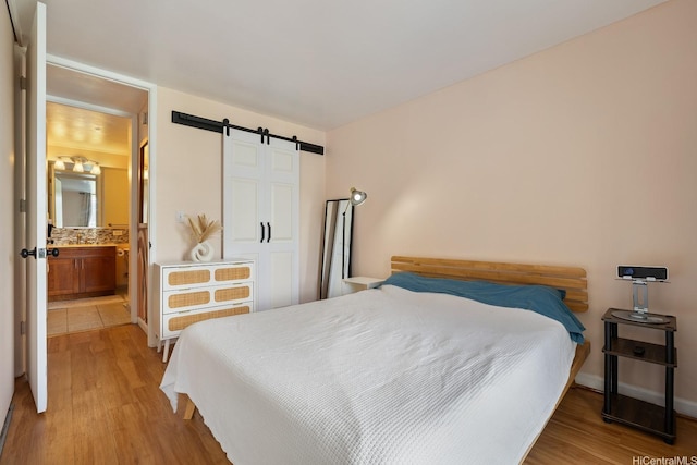 2452 Tusitala St Unit 1207, Honolulu, HI 96815 - bedroom featuring a barn door, light wood finished floors, and ensuite bathroom