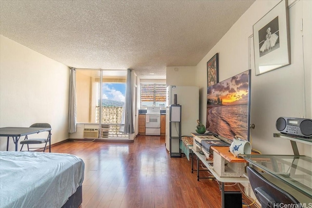 747 Amana St Unit 1405, Honolulu, HI 96814 - bedroom featuring a textured ceiling, wood finished floors, an AC wall unit, and freestanding refrigerator