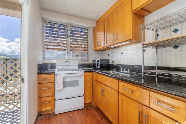747 Amana St Unit 1405, Honolulu, HI 96814 - kitchen featuring electric stove, stainless steel microwave, a sink, dark wood-style floors, and dark stone counters