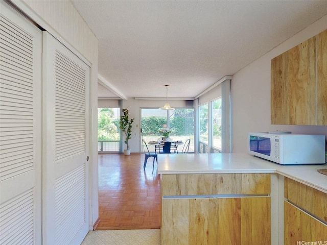 94-1036 Leomana Pl, Waipahu, HI 96797 - kitchen featuring white microwave, a peninsula, light countertops, and decorative light fixtures