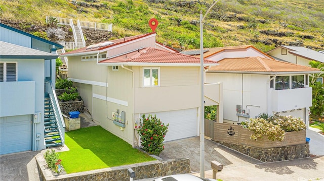 1441 Honokahua St, Honolulu, HI 96825 - view of side of property featuring a tiled roof, stairs, an attached garage, driveway, and stucco siding