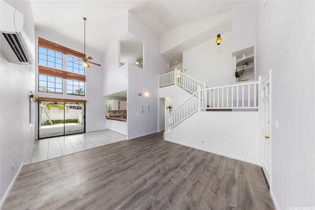 91-1011 Aeoia St Unit A, Ewa Beach, HI 96706 - unfurnished living room with a towering ceiling, a wall mounted AC, ceiling fan, stairs, and wood finished floors