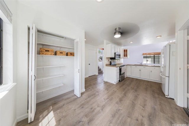 91-1011 Aeoia St Unit A, Ewa Beach, HI 96706 - kitchen with stainless steel appliances, white cabinets, light wood-style flooring, a sink, and recessed lighting