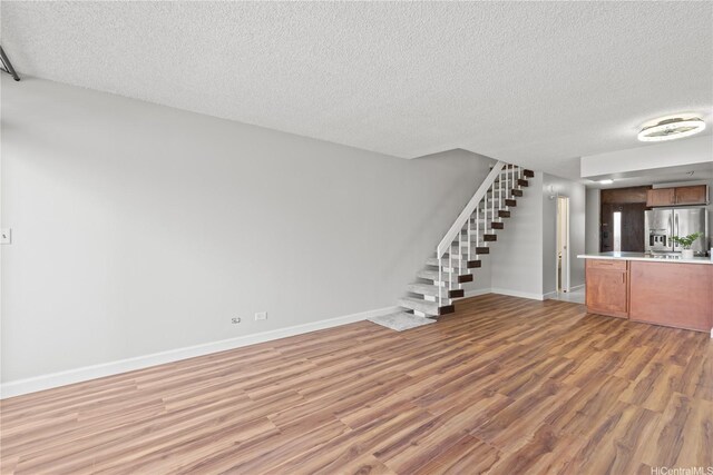 500 University Ave Unit 509, Honolulu, HI 96826 - unfurnished living room featuring a textured ceiling, stairs, light wood-style flooring, and baseboards