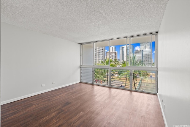 500 University Ave Unit 509, Honolulu, HI 96826 - empty room featuring expansive windows, a view of skyline, wood finished floors, a textured ceiling, and baseboards