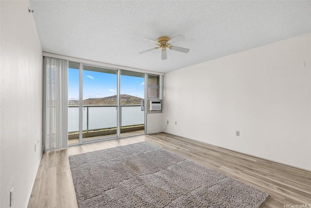 3009 Ala Makahala Pl Unit 905, Honolulu, HI 96818 - unfurnished room featuring floor to ceiling windows, ceiling fan, light wood-style floors, and a textured ceiling