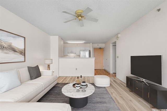 3009 Ala Makahala Pl Unit 905, Honolulu, HI 96818 - living area featuring light wood finished floors, a ceiling fan, and a textured ceiling