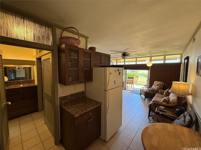 255 Kepuhi Pl Unit 4A02-1242, Maunaloa, HI 96770 - kitchen featuring a ceiling fan, freestanding refrigerator, light tile patterned floors, dark brown cabinetry, and glass insert cabinets