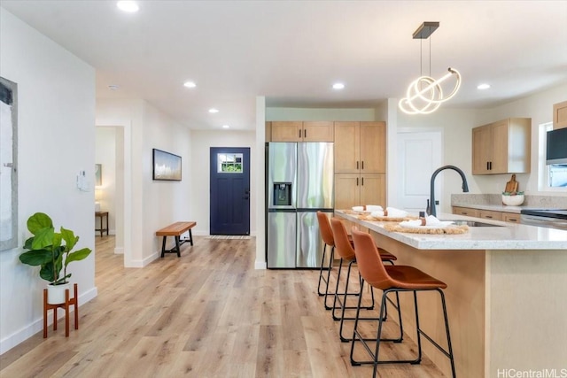 1504 Ainakoa Ave, Honolulu, HI 96821 - kitchen featuring stainless steel fridge, light brown cabinets, a sink, a kitchen bar, and light wood-style flooring