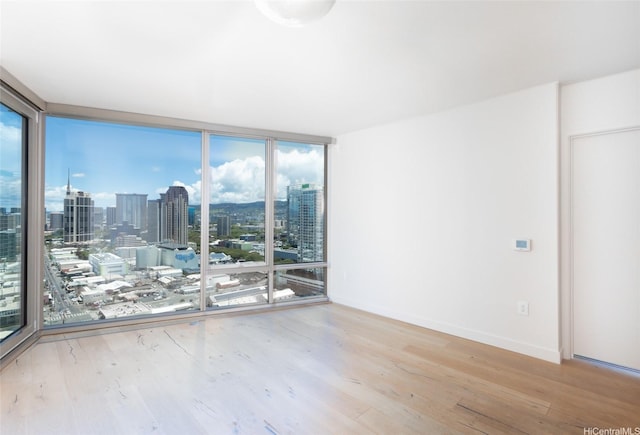 1001 Queen St Unit 2415, Honolulu, HI 96814 - spare room with a wall of windows, wood finished floors, a skyline view, and baseboards