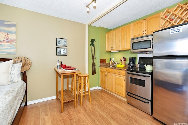 2345 Ala Wai Blvd Unit 1805, Honolulu, HI 96815 - kitchen with appliances with stainless steel finishes, light brown cabinetry, light wood-style flooring, a sink, and a textured ceiling
