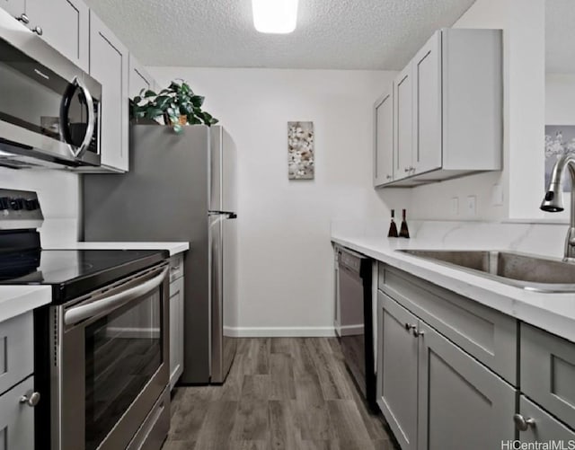 95-510 Wikao St Unit B201, Mililani, HI 96789 - kitchen with stainless steel appliances, a sink, gray cabinets, a textured ceiling, and wood finished floors