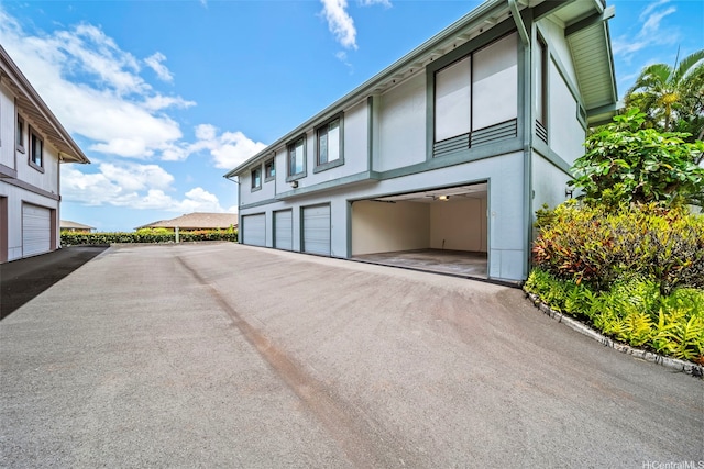 98-1712 Kaahumanu St Unit 11A, Pearl City, HI 96782 - view of side of home with stucco siding, asphalt driveway, and an attached garage