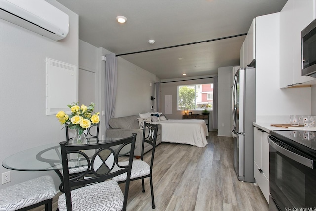 91-3575 Kamolehonua St Unit 902, Ewa Beach, HI 96706 - kitchen with appliances with stainless steel finishes, a wall mounted AC, white cabinets, open floor plan, and light wood finished floors