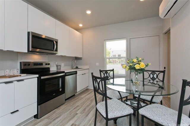 91-3575 Kamolehonua St Unit 902, Ewa Beach, HI 96706 - kitchen with appliances with stainless steel finishes, a wall unit AC, a sink, light countertops, and light wood-type flooring