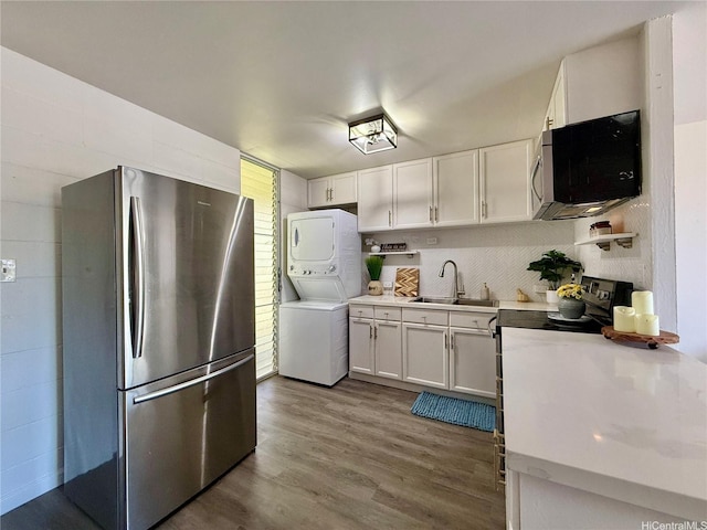 95-2055 Waikalani Pl Unit B204, Mililani, HI 96789 - kitchen with appliances with stainless steel finishes, stacked washer and clothes dryer, a sink, white cabinets, and dark wood-style floors