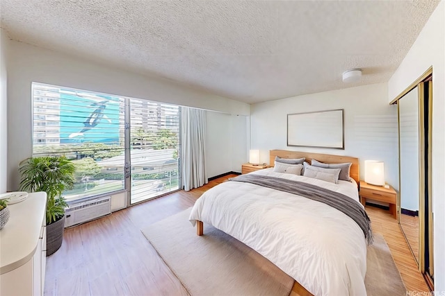 1911 Kalakaua Ave Unit 411, Honolulu, HI 96815 - bedroom featuring a textured ceiling, light wood finished floors, and a wall unit AC