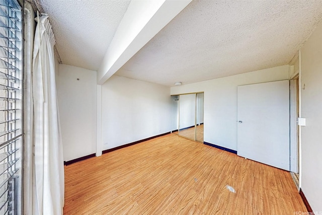 1911 Kalakaua Ave Unit 411, Honolulu, HI 96815 - unfurnished bedroom featuring wood finished floors, a textured ceiling, baseboards, and a closet
