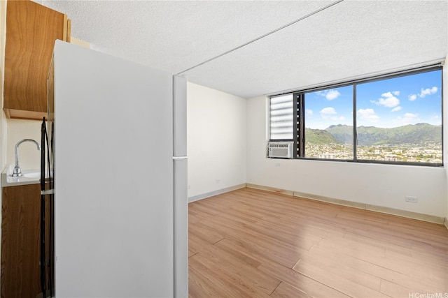 444 Niu St Unit 3806, Honolulu, HI 96815 - unfurnished room with a textured ceiling, light wood finished floors, a mountain view, baseboards, and cooling unit