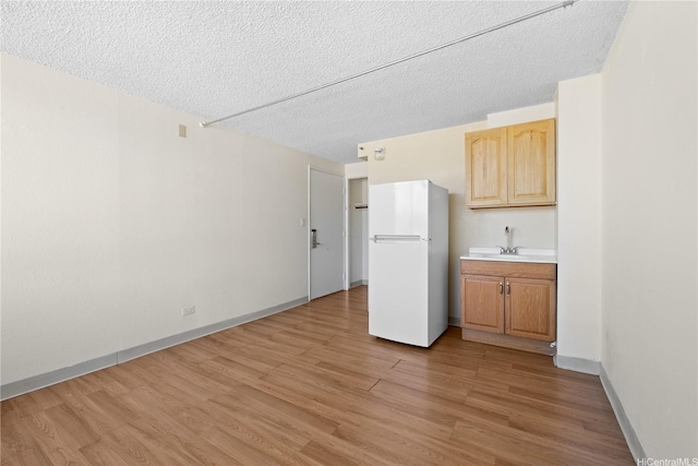 444 Niu St Unit 3806, Honolulu, HI 96815 - kitchen featuring freestanding refrigerator, a sink, light wood-type flooring, a textured ceiling, and light countertops