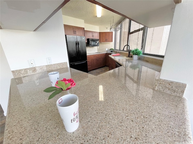1221 Victoria St Unit 1205, Honolulu, HI 96814 - kitchen featuring black appliances, a sink, brown cabinets, light stone counters, and a peninsula