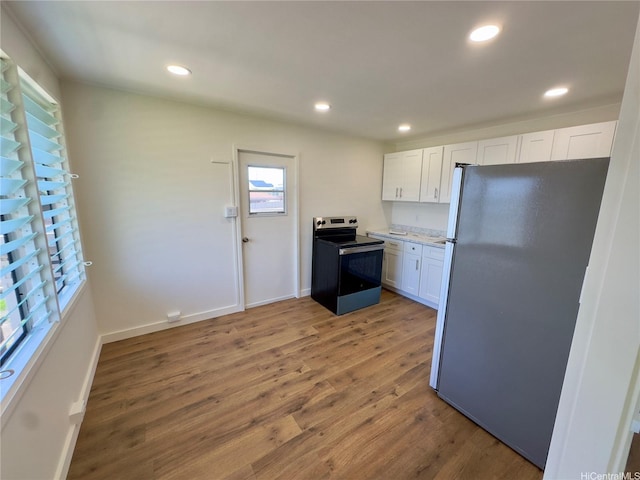 1846 Kilohi St, Honolulu, HI 96819 - kitchen featuring stainless steel electric stove, freestanding refrigerator, wood finished floors, white cabinets, and recessed lighting