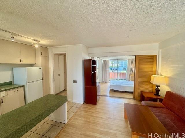 417 Nohonani St Unit 513, Honolulu, HI 96815 - living room with a textured ceiling, rail lighting, and light wood-style floors