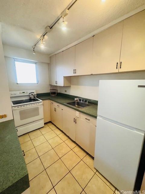 417 Nohonani St Unit 513, Honolulu, HI 96815 - kitchen featuring white appliances, track lighting, dark countertops, and light tile patterned flooring
