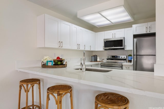 94-1444 Okupu St, Waipahu, HI 96797 - kitchen with stainless steel appliances, a sink, white cabinetry, and light stone counters