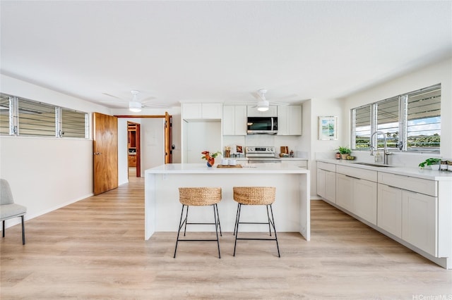 902 Wanaao Rd, Kailua, HI 96734 - kitchen with a sink, appliances with stainless steel finishes, a breakfast bar area, light wood-style floors, and a ceiling fan