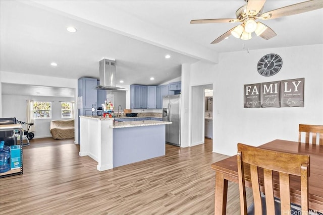 87-1698 Farrington Hwy Unit L, Waianae, HI 96792 - kitchen featuring island range hood, stainless steel refrigerator with ice dispenser, light wood-style floors, a peninsula, and blue cabinetry