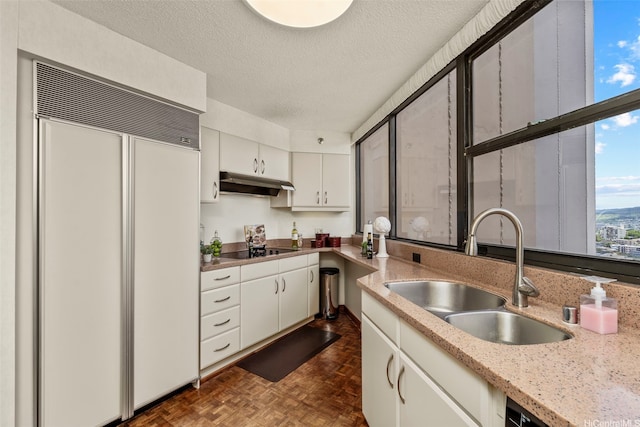 1221 Victoria St Unit 3205, Honolulu, HI 96814 - kitchen featuring paneled built in refrigerator, a sink, under cabinet range hood, black electric cooktop, and white cabinetry