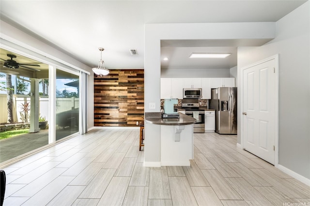 91-1200 Keaunui Dr Unit 204, Ewa Beach, HI 96706 - kitchen with stainless steel appliances, dark countertops, a kitchen breakfast bar, white cabinetry, and wood tiled floors