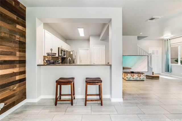 91-1200 Keaunui Dr Unit 204, Ewa Beach, HI 96706 - kitchen with appliances with stainless steel finishes, white cabinetry, a kitchen bar, a peninsula, and backsplash